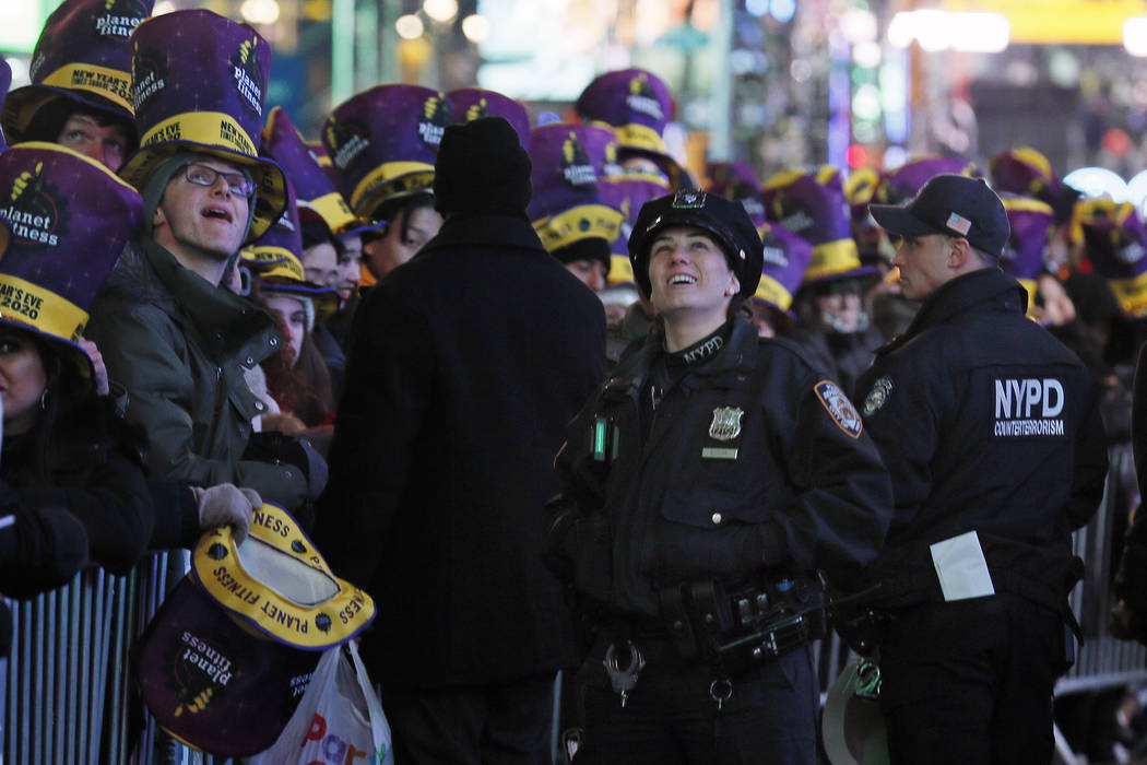 New York City police officers and revelers wait in New York's Times Square, Tuesday, Dec. 31, 2 ...