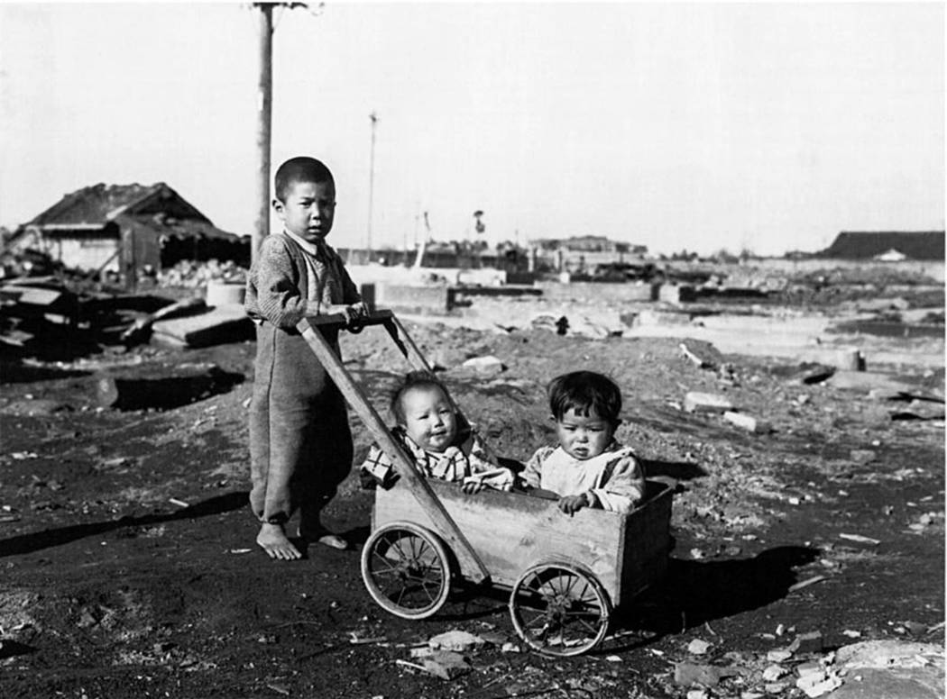 A Japanese boy pushes two younger children in a wagon in this photograph shot in Hiroshima, Jap ...