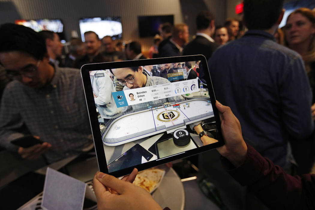 People watch real-time puck and player tracking technology on display during an NHL hockey game ...