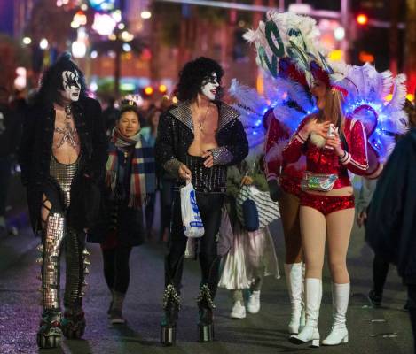 Showgirls, right, share a moment with street performers dressed in Kiss attire on the Strip on ...