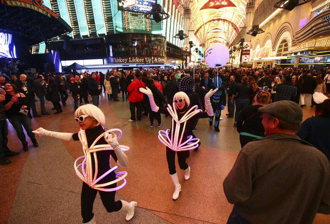 Costumed performers with the Champagne Creative Group walk through the crowd as New Year's Eve ...