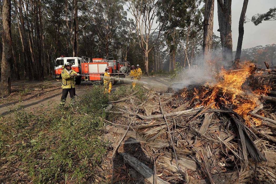 Firefighters battles a fire near Bendalong, Australia, Friday, Jan. 3, 2020. Navy ships plucked ...