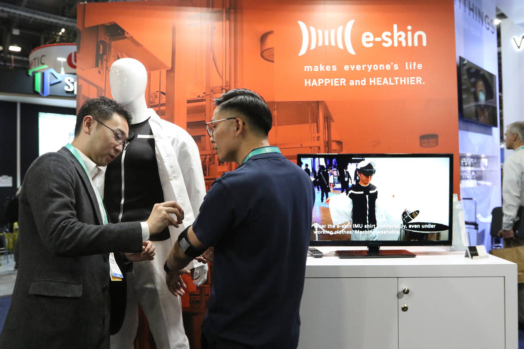 Attendees test how the E-Skin suit, a wearable fitness item, works at the CES trade show at the ...