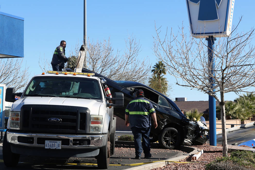 Tow truck operators work to remove a vehicle that crashed into and was partially propped up on ...