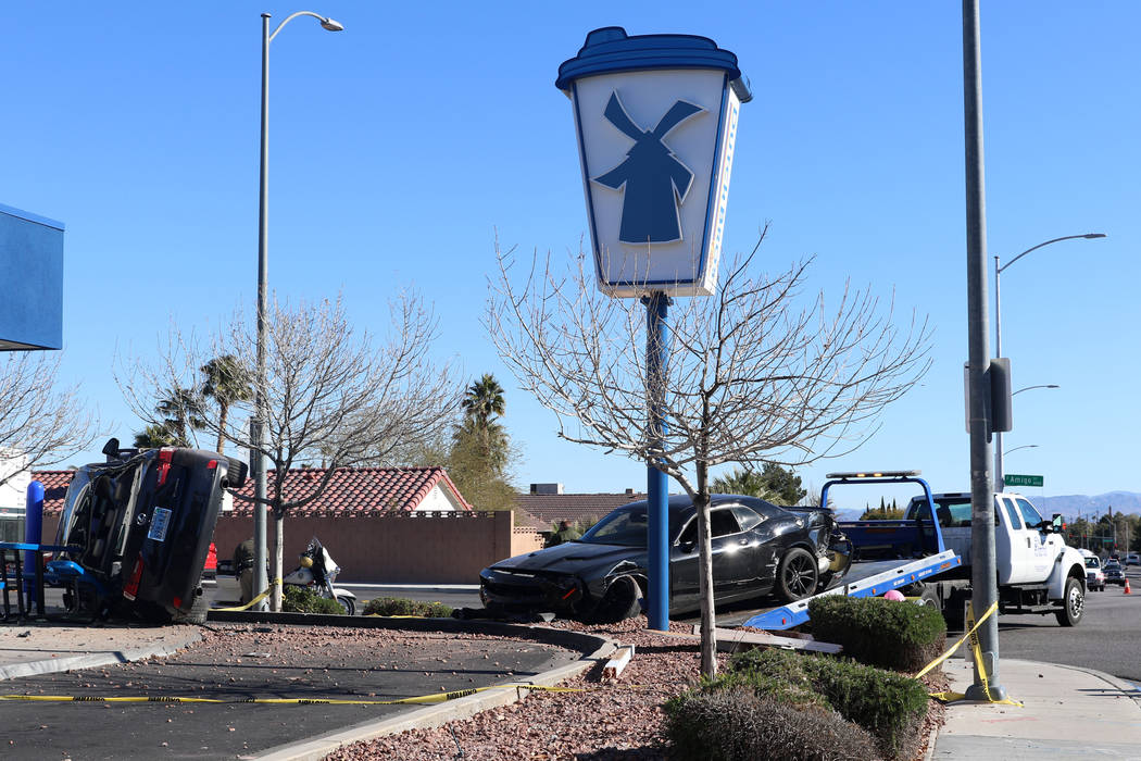 Tow truck operators remove a vehicle that crashed into and was partially propped up on top of a ...