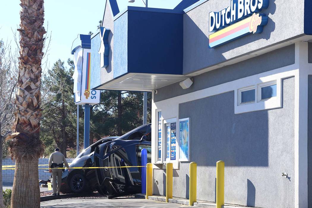 A Las Vegas Metro Police officer walks the scene of a car crash outside a Dutch Bros coffee sho ...