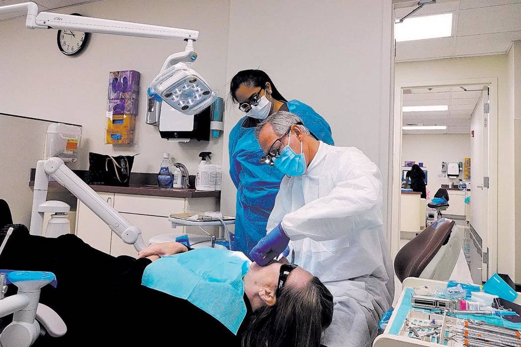 Dr. Phillip Devore, DDS, associate professor at School of Dental Medicine, works with a student ...