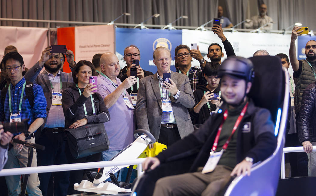Attendees watch Segway Vice President Chen Huang demonstrate the S-Pod transporter at CES at th ...