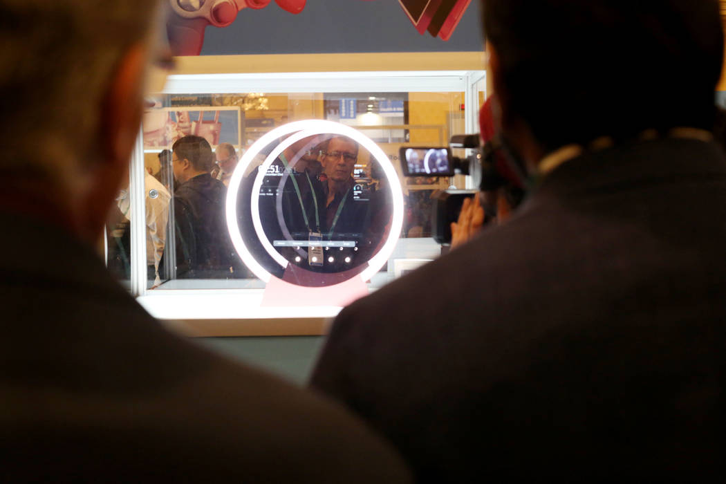 Individuals look at the Lumini Home Al Beauty & Lifestyle Assistant, a smart mirror display ...