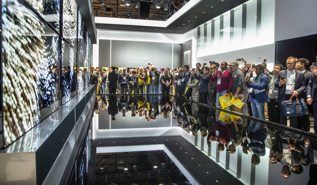 Attendees check out the new LG Signature OLED R televisions during CES Day 1 in Central Hall of ...
