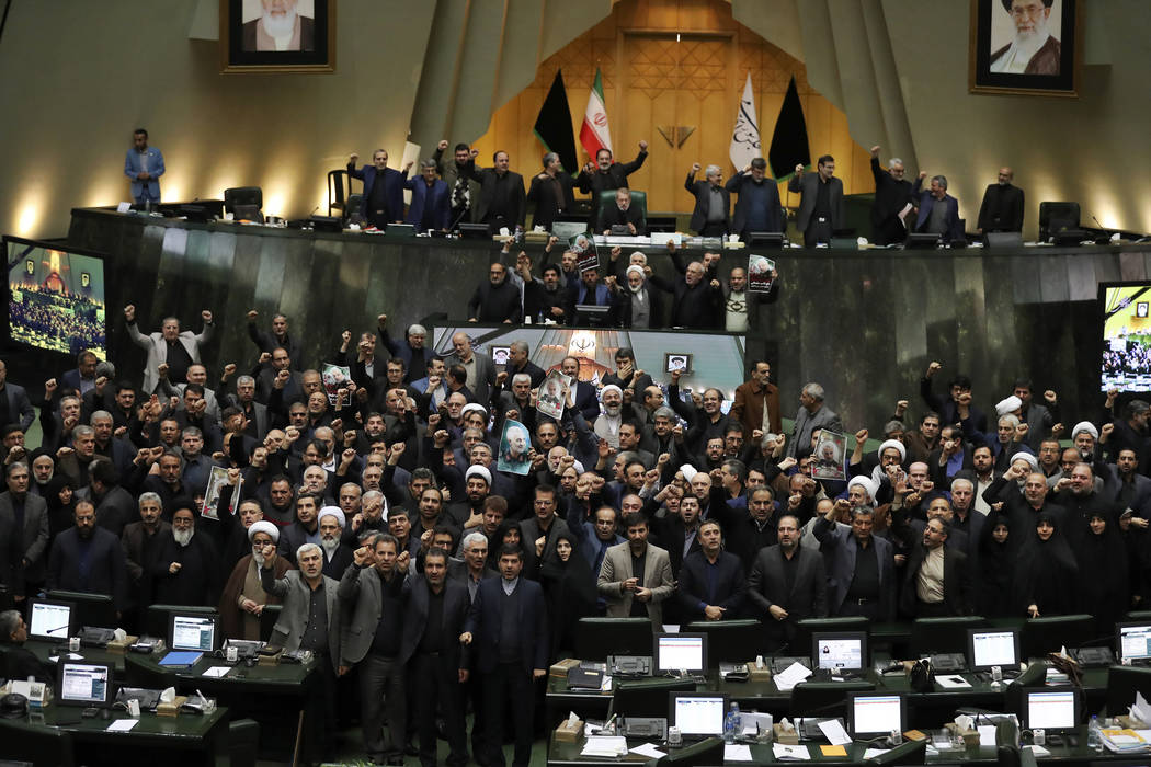 Iranian lawmakers chant slogans as some of them hold posters of Gen. Qassem Soleimani, who was ...