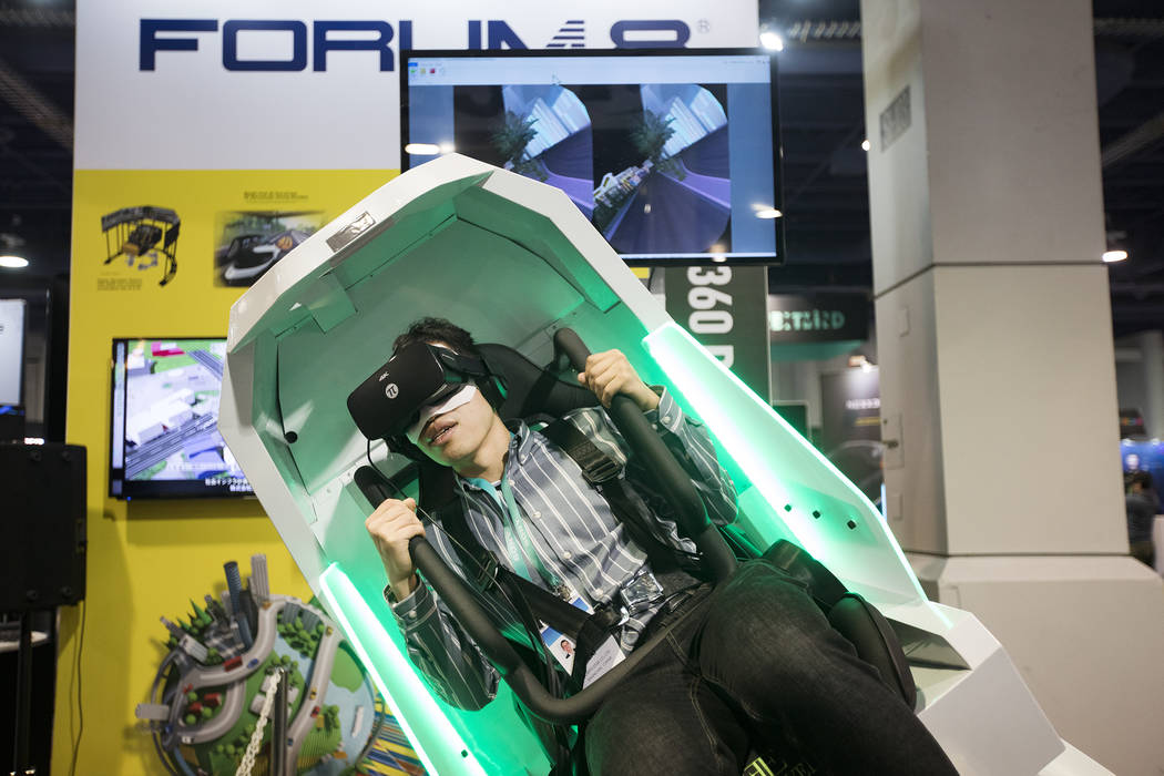 Shunjie Cai, of Singapore, tries out the VR360 by FORUM8, a ride and 360 degree simulator, at C ...