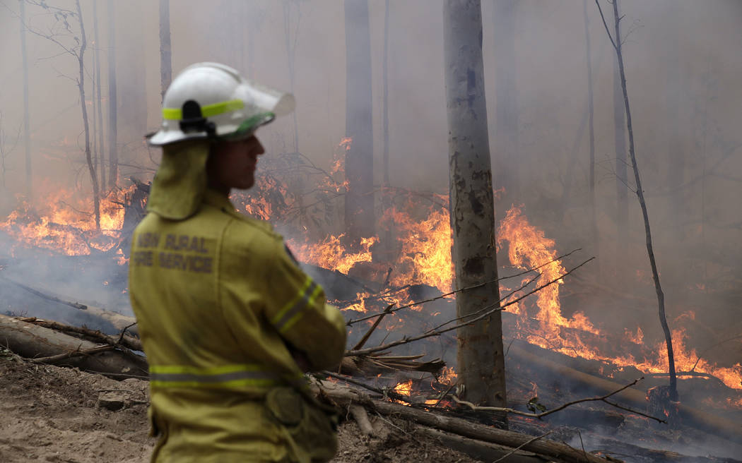 A firefighter keeps an eye on a controlled fire as they work at building a containment line at ...