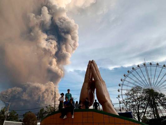 People watch as the Taal volcano spews ash and smoke during an eruption in Tagaytay, Cavite pro ...