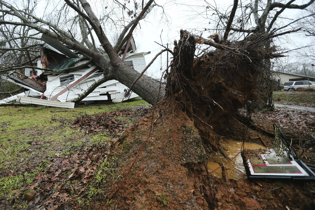 A downed tree rests on top of Anthony Dalrymple's home on Community Road in Baldwyn, Miss., aft ...