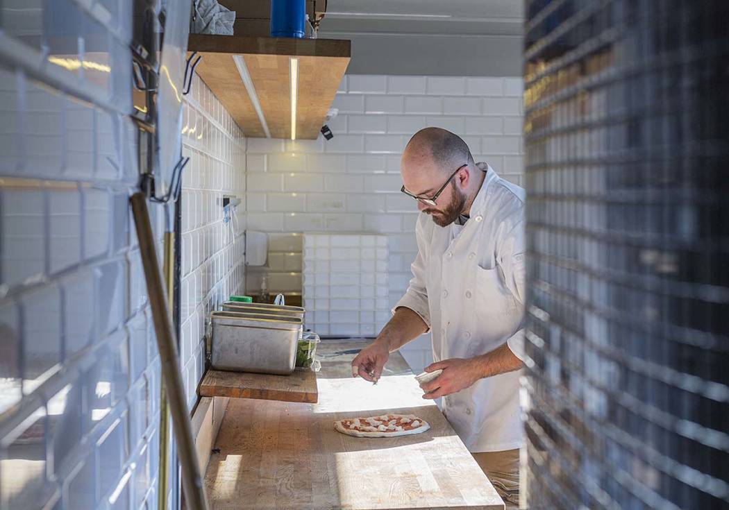 Chef Bartosz Wawrzyszak, owner of the Custom Pizza Truck, places gorgonzola on dough in his foo ...