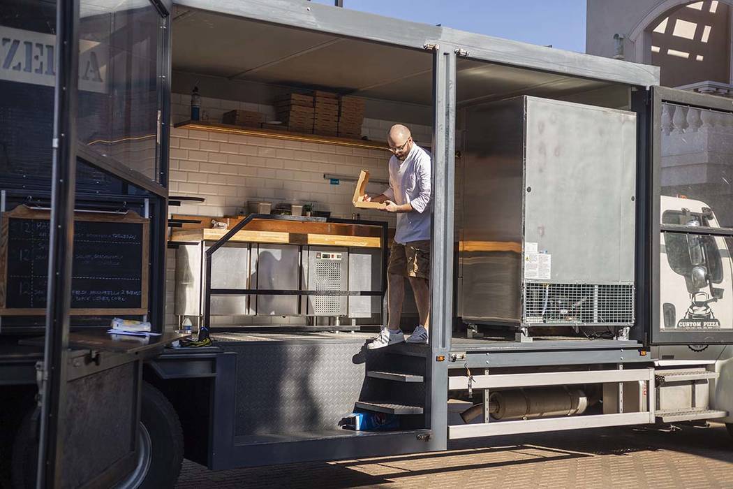 Chef Bartosz Wawrzyszak, owner of the Custom Pizza Truck, delivers a pizza to a customer from h ...
