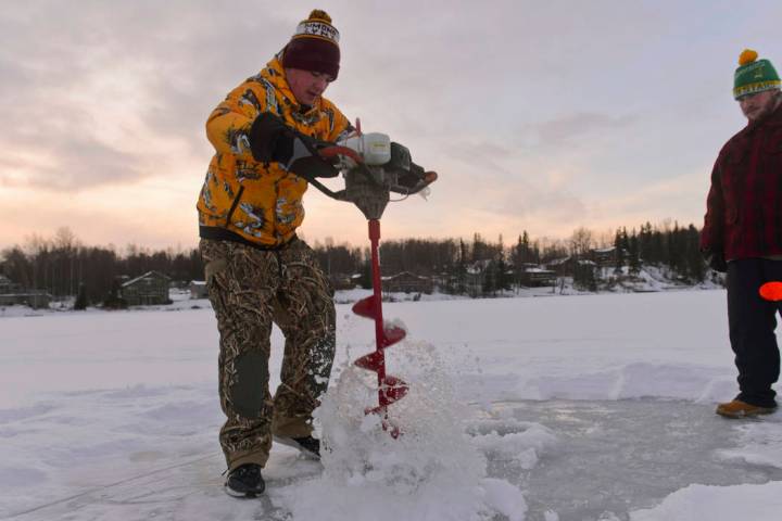 In this Dec. 27, 2019 photo Matthew Driskell, right, looks on as Taylor Baker uses an auger to ...