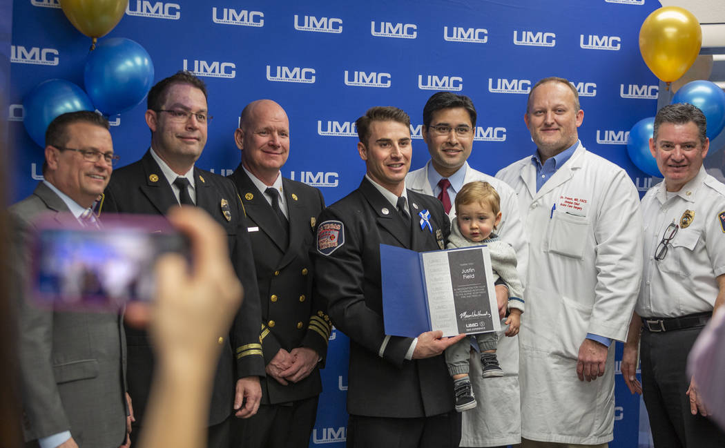 Las Vegas Fire and Rescue firefighter Justin Field, center holds his son, 1-year-old Levi Field ...