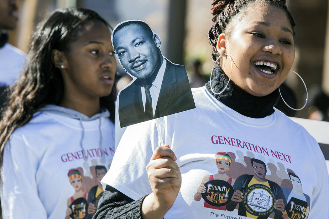 I'yanne Davis holds a sign showing the image of Martin Luther King Jr. during the MLK parade in ...