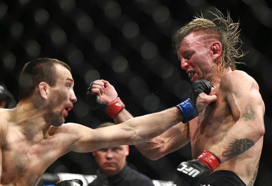 Tim Elliott, right, takes a hit from Askar Askarov during their flyweight bout at UFC 246 at T- ...