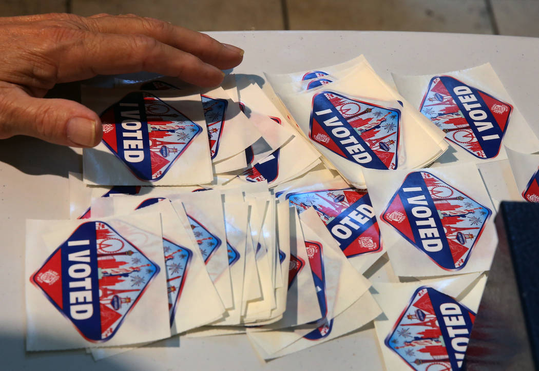 Robert Elvin, an election official, displays "I Voted" stickers at a polling station ...