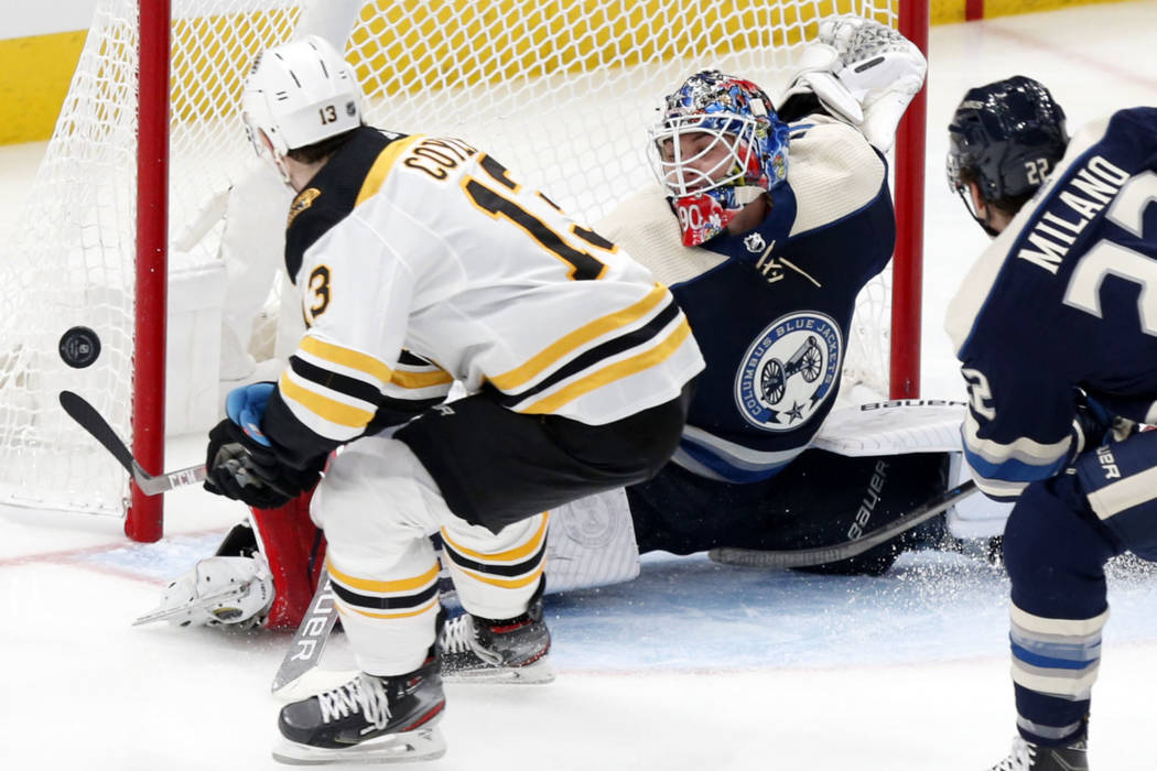 Columbus Blue Jackets goalie Elvis Merzlikins, center, of Latvia, stops a shot by Boston Bruins ...