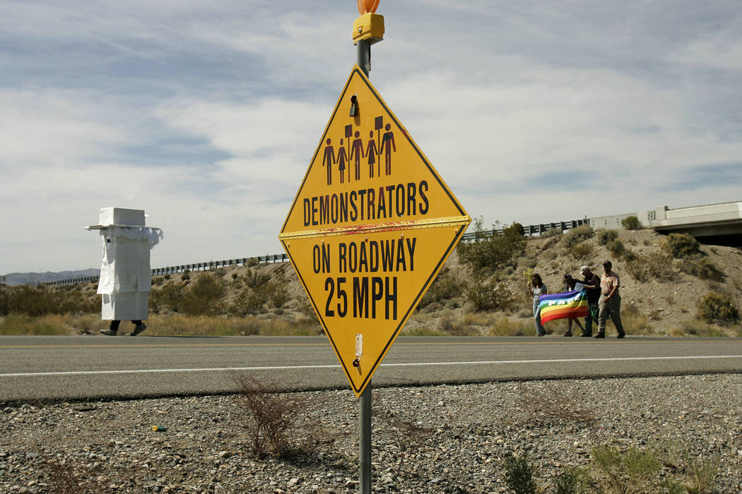 Anti-nuclear demonstrators, some in costume, pass by a sign that warns motorists of their prese ...