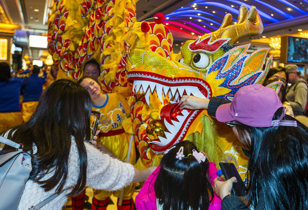 People place money into the mouth of a dragon for good fortune as dancers from the Yau Kung Moo ...