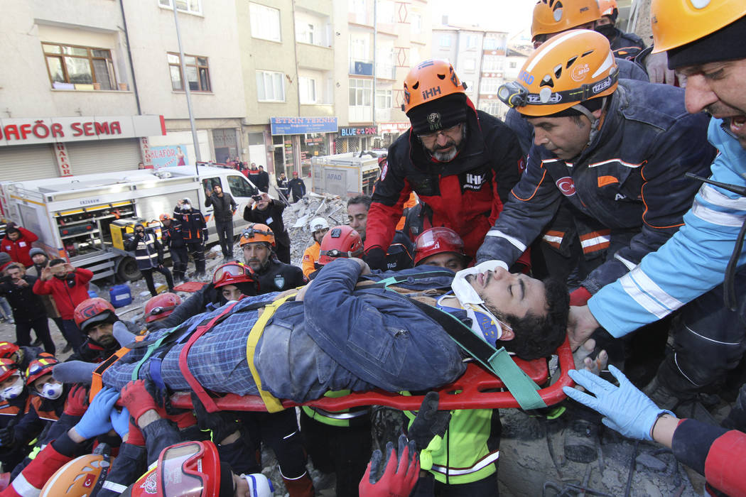 Rescue workers carry a wounded man that was found alive in the rubble of a building destroyed o ...