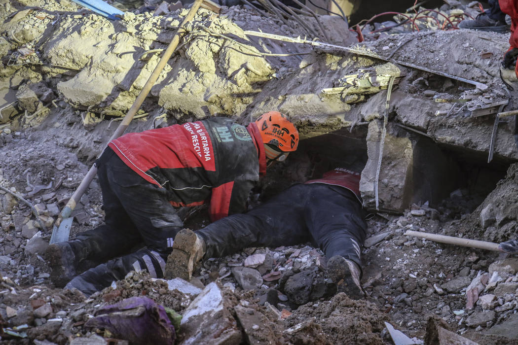 Rescue workers try to save people trapped under debris following a strong earthquake that destr ...
