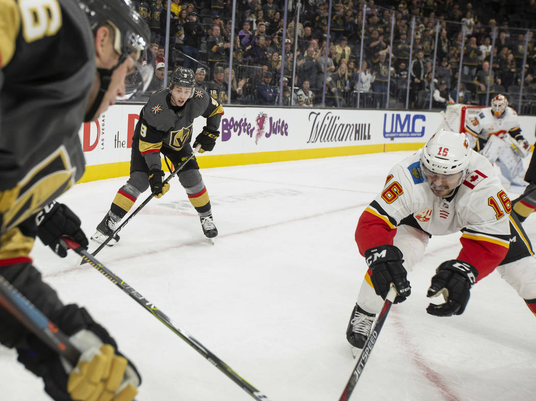 Golden Knights center Cody Glass (9) eyes the puck as Calgary Flames center Tobias Rieder (16) ...