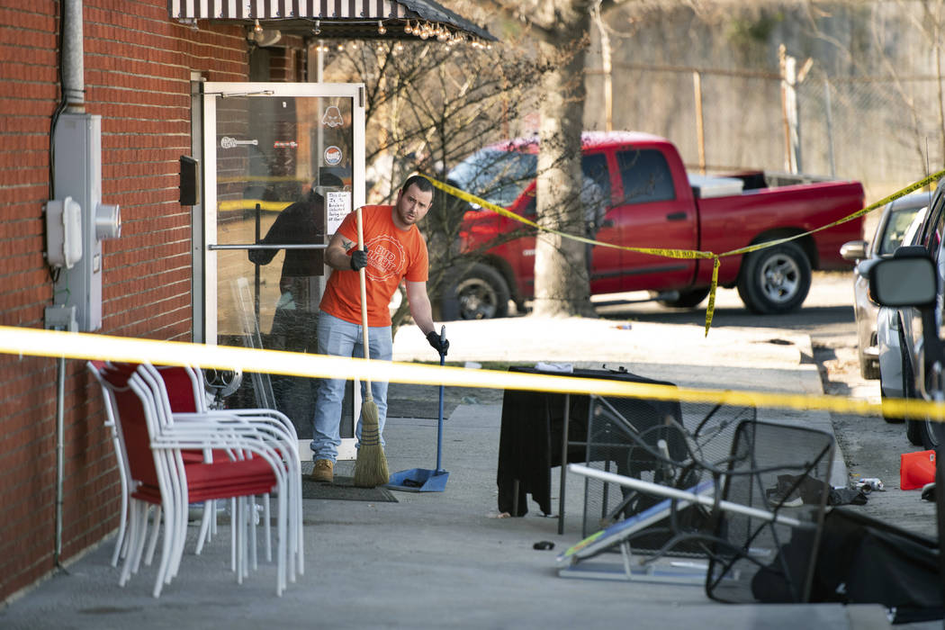 A man cleans up in front of Mac's Lounge, the scene of an early morning bar shooting, Sunday, J ...