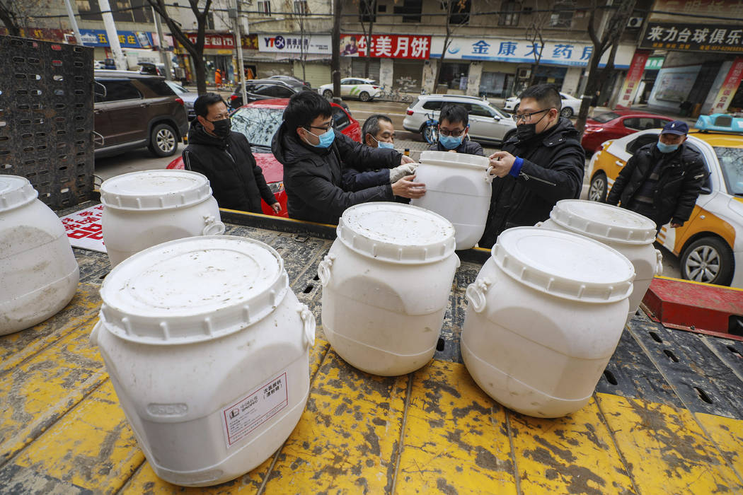 Workers unload canisters of disinfectant from a truck in Wuhan in central China's Hubei Provinc ...