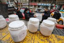 Workers unload canisters of disinfectant from a truck in Wuhan in central China's Hubei Provinc ...
