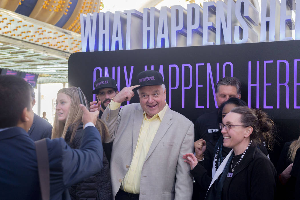 Nevada Gov. Steve Sisolak, center, wears a hat with Las Vegas' new slogan, " What Happens ...