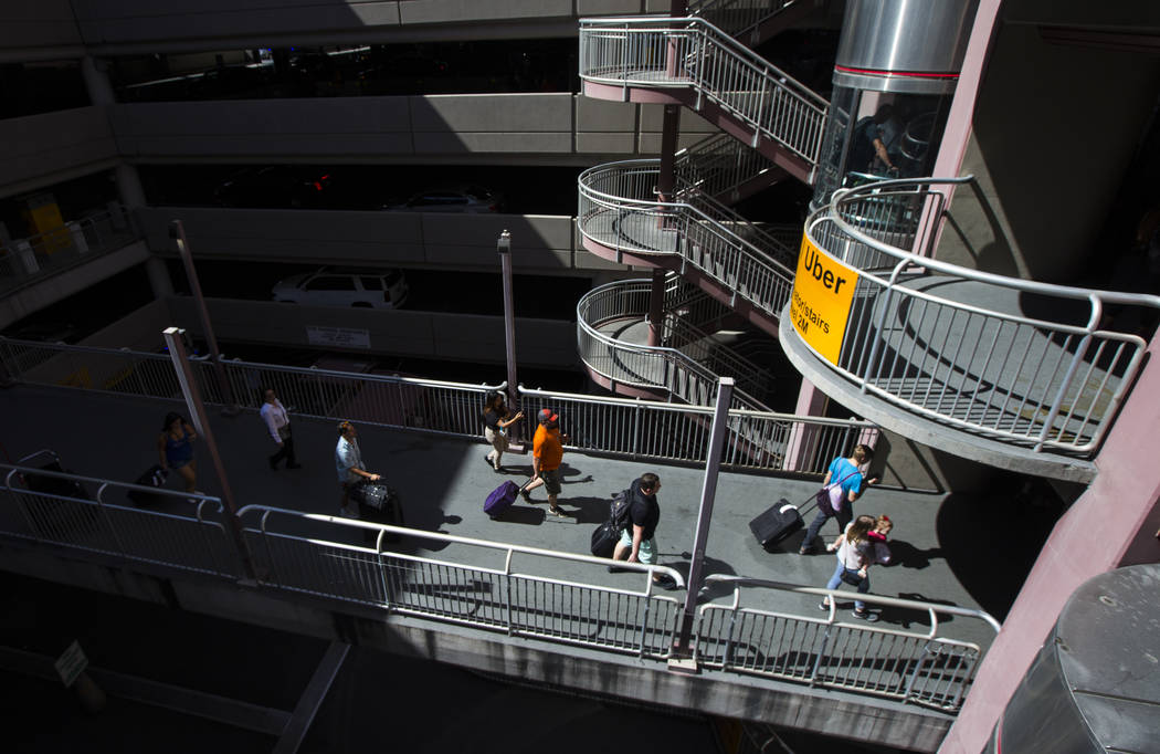 Passengers make their way to ride-hailing services and parking after arriving at McCarran Inter ...