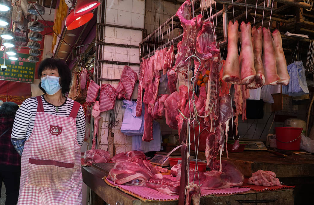 A vendor wears a face mask selling meat at a market in Hong Kong, Friday, Jan. 31, 2020. The Wo ...