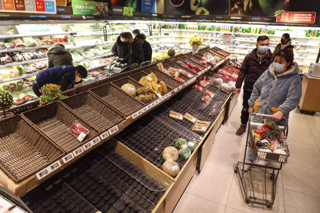 FILE - In this Jan. 25, 2020 photo, shoppers wearing face masks look for groceries near mostly ...