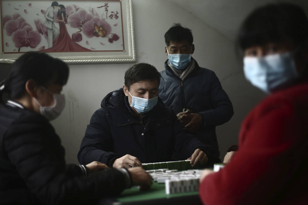 In this Jan. 25, 2020 photo, family members wear masks as they play mahjongg during a Lunar New ...
