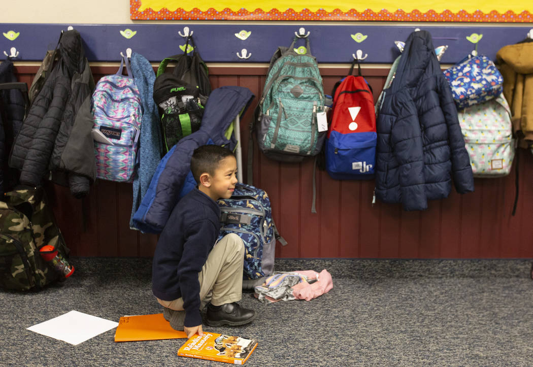 Aiden Hix retrieves books from his backpack before reading group at American Preparatory Academ ...