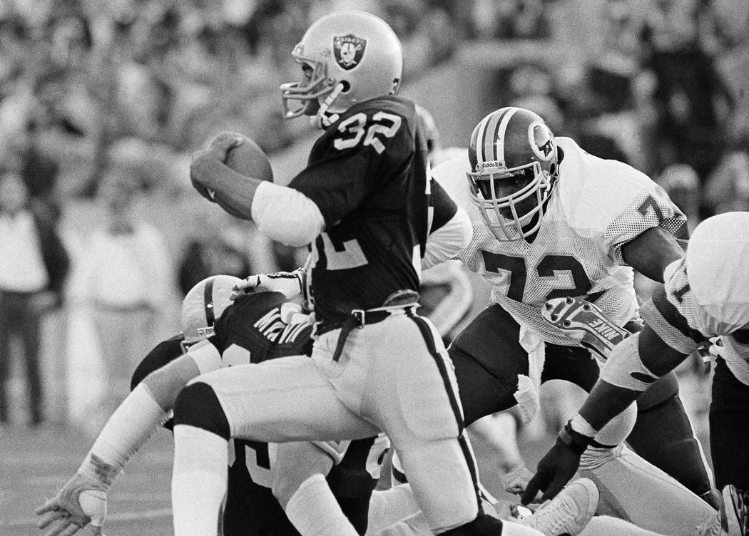 Los Angeles Raiders running back Marcus Allen runs with the ball after taking a handoff from qu ...