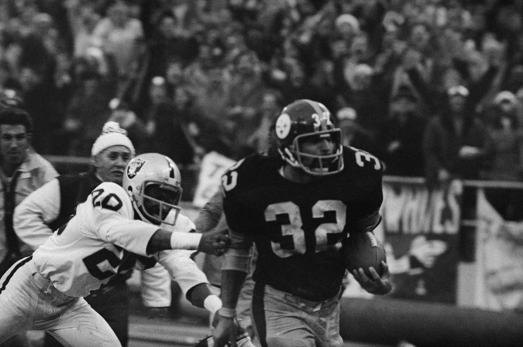 Franco Harris (32) of the Pittsburgh Steelers eludes a tackle by Jimmy Warren of the Oakland Ra ...