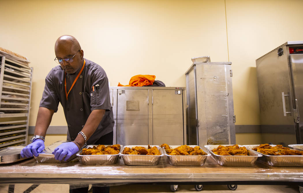Sarif El-Amin, of Three Square food bank, packages fried chicken and other surplus banquet food ...
