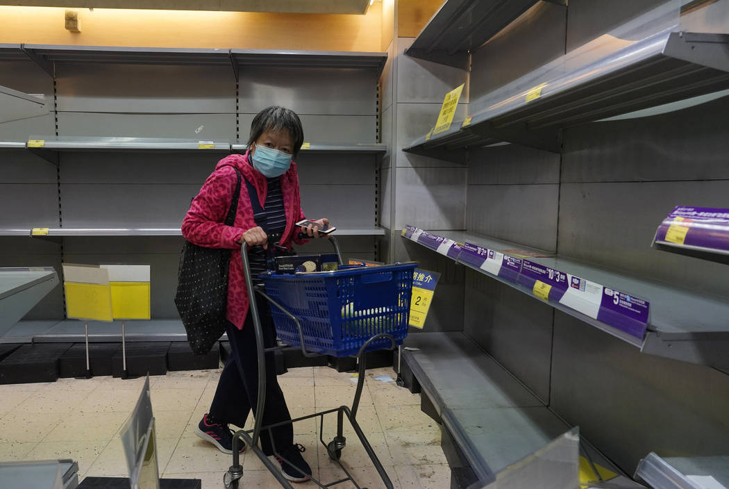 A woman wearing face mask walks past empty shelf of tissue papers at a supermarket in Hong Kong ...
