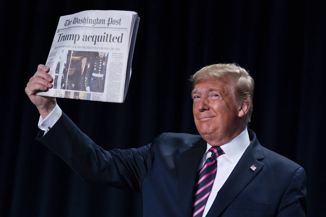 President Donald Trump holds up a newspaper with the headline that reads "Trump acquitted& ...