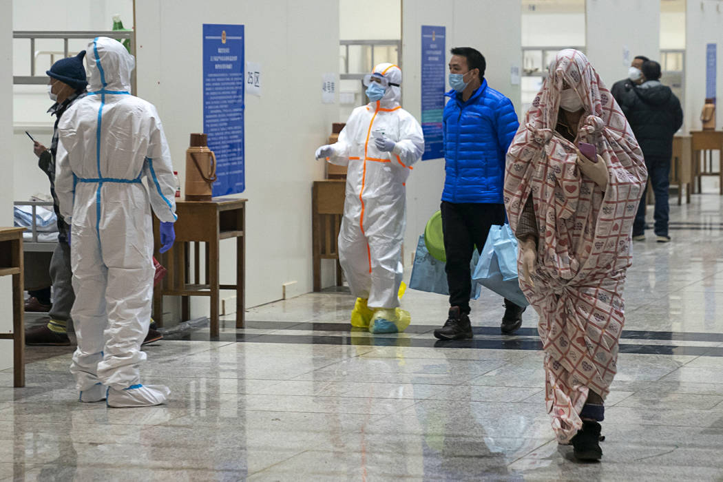 In this Wednesday, Feb. 5, 2020, photo, medical workers in a protective suit help patients who ...