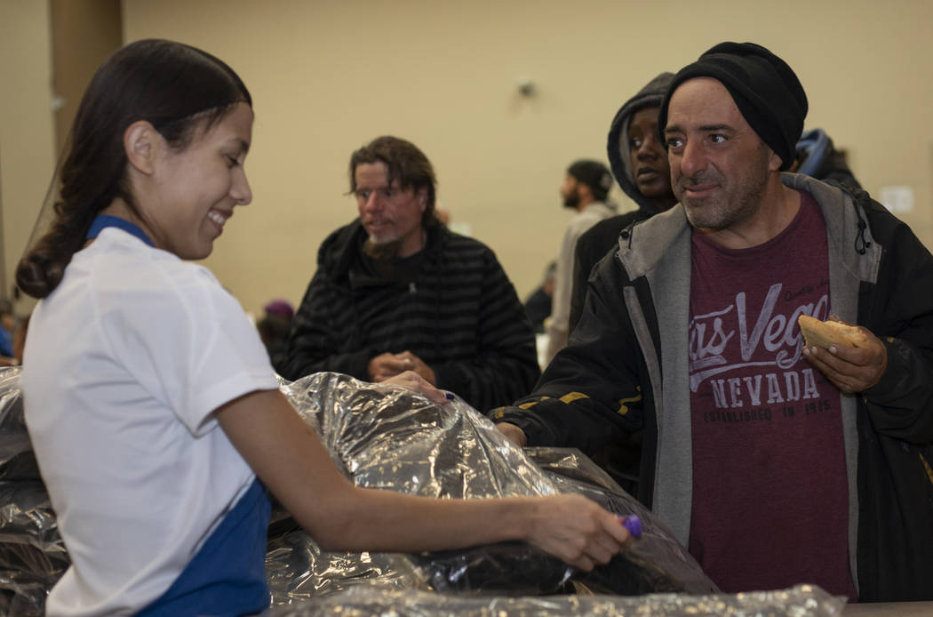 UNLV student Vicky Castellanos hands a CITYPAK backpack to Victor de Mayo at the Las Vegas Resc ...