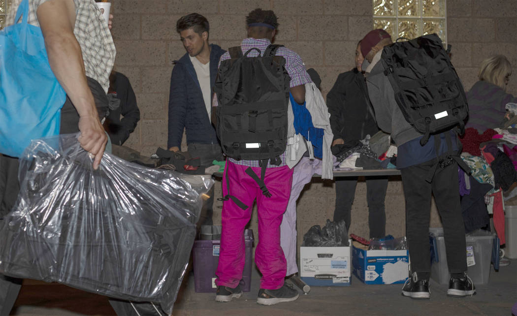 Two individuals wear CITYPAK backpacks as they look through donated clothing as a person walks ...