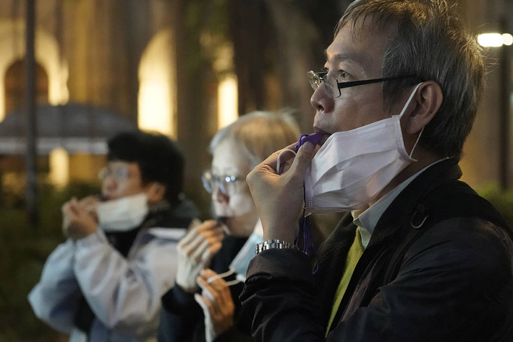 People with masks, blow whistles to representing whistleblower during a vigil for Chinese docto ...